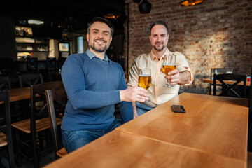 Friends toasting beer glasses celebrating at bar