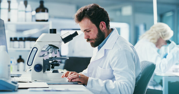 Microscope, man and scientist in laboratory for pharmaceutical research, study or experiment. Biotechnology, professional and male biologist typing with clinical development, science or innovation.