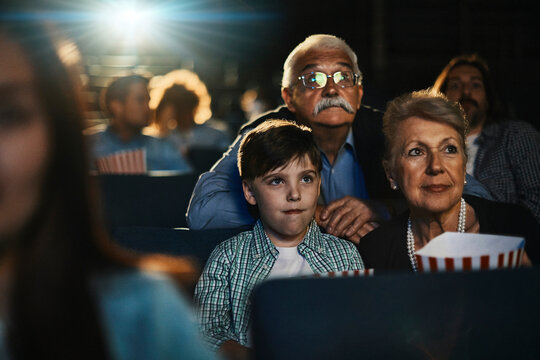 Grandparents and grandson watching a movie at the cinema