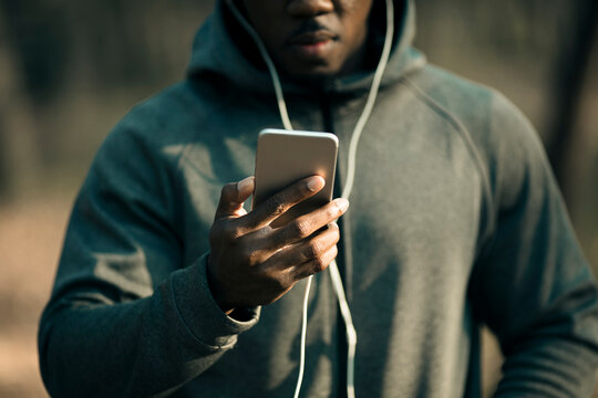 Man using smartphone with earphones during outdoor workout