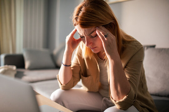 Stressed woman with headache on sofa at home