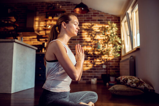 Young woman meditating at home in sunlight