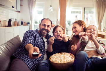 Fototapeta premium Happy family watching television and eating popcorn at home