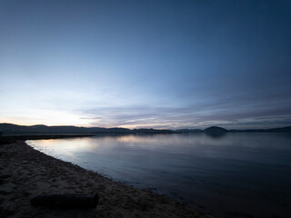 Beach shore reflecting sunset colors during tranquil blue hour © larrui