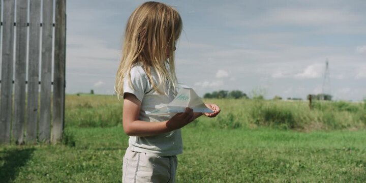 Young boy with a paper airplane in a countryside field
