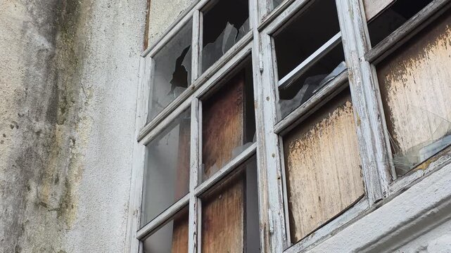 Derelict building with weathered walls and broken windows showing decay and abandonment in an old industrial factory