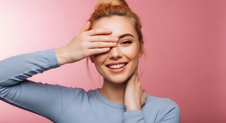 Woman covering face with hand smiling pink background