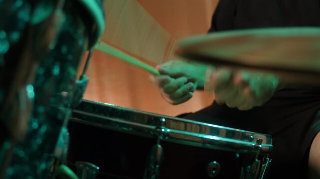 Drummer playing on concert, close up in studio, drummer hands hit the drum cymbal with drumstick in a dark studio. Drummer plays the drums in the recording studio. Music band rehearsal