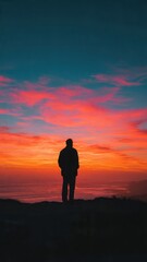 Obraz premium Solitary figure watches breathtaking sunset over sea