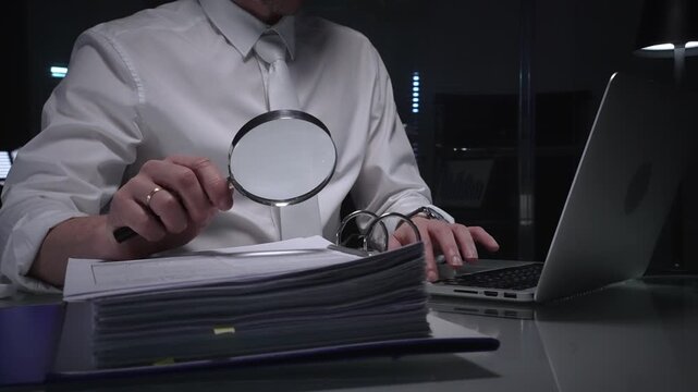 Businessman analyzing financial documents and paperwork at desk, working overtime in a dark office, researching data for investigation. Audit and taxes in business