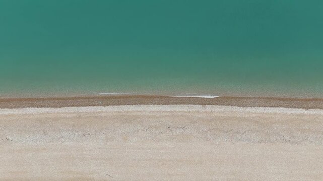 Birds Eye View Drone shot of English Coastline on a calm cloudy day, with stone beach and soft waves