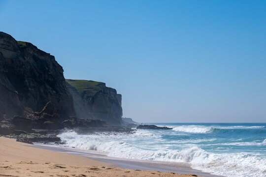 Steilk&uuml;ste Portugal, t&uuml;rkisblaues Meer, Brandung mit hohen Wellen, windig, Meeresbrise am einsamen idyllischen Sandstrand