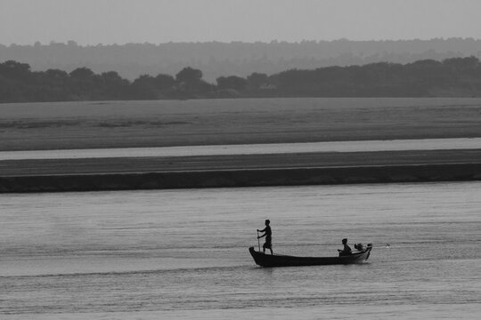 Silhouette of a small boat on Irrawaddy river at dawn.