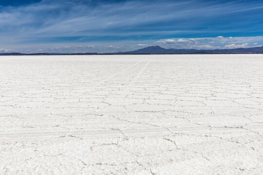 Endless White Hexagonal Salt Crust Stretching to Mountain Horizon at Salar de Uyuni, Bolivia &ndash; Dry Season Landscape