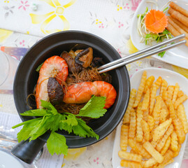Thai glass noodles with shrimp cooked in clay pot, known as Goong Ob Woon Sen.  Traditional Thai seafood dish with vermicelli noodles, herbs and spices served with side dishes. © Hathaichanok