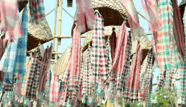 Traditional Checkered Cloth Strips Hanging Under Woven Bamboo Hats