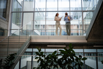 Business colleagues having meeting and conversation overlooking modern office atrium