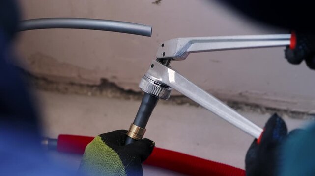 Worker Expanding Plastic Pipe with PEX Pipe Expander Tool