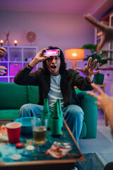 People enjoying fun guessing game on mobile application at home party, friends acting out charades for entertainment