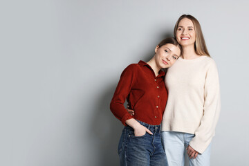 Fototapeta premium Mother and her teenage daughter on light grey background, space for text