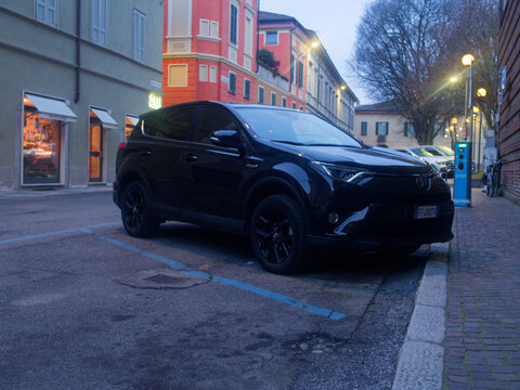 Black Toyota RAV4 parked on a street in a European town at dusk