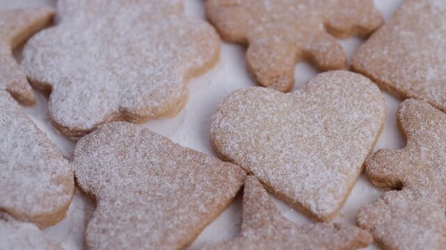 Closeup of freshly baked cookies featuring decorative shapes and light dusting, Detailed view of ovenfresh cookies decorated with heart and star patterns on parchment paper