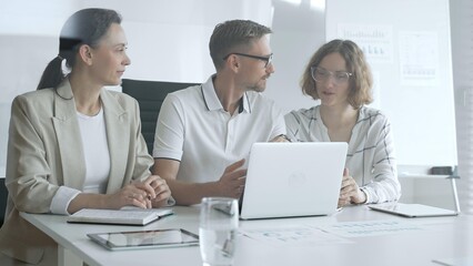 Fototapeta premium Business team collaborating on a project, analyzing data on a laptop during a productive office meeting, demonstrating teamwork and problem solving skills