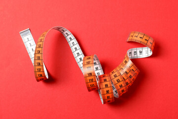 One measuring tape on red background, top view