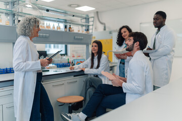 Obraz premium Senior scientist mentoring diverse students in laboratory