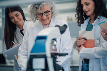 Fototapeta premium Senior female scientist teaching young women in laboratory