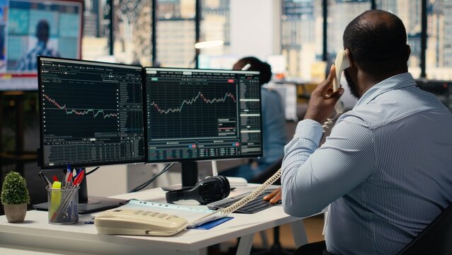 Worried portfolio managers making telephone calls in response to Black Swan event disruption. Panicked prop firm workers evaluate stock market impact of unexpected recession