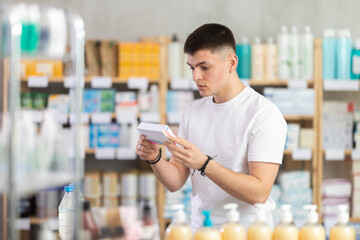 Focused young guy choosing pill box and making decisions about pharmaceuticals and health care in...