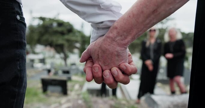 Graveyard, people and holding hands for memorial service, family mourning and compassion for comfort. Sympathy, care and senior woman with son for emotional support, loss and grieving at cemetery