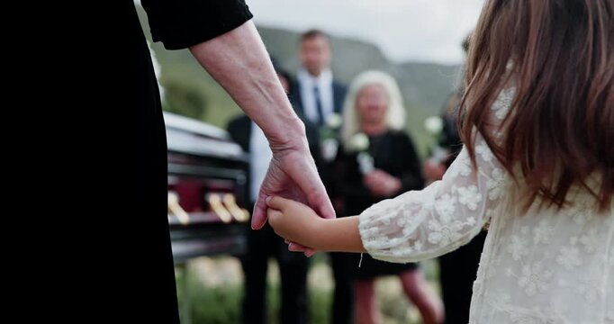 Person, holding hands and kid at graveyard for funeral ceremony, burial service and mourning loss. Casket, family and child with empathy, emotional ritual and tribute gathering at farewell memorial