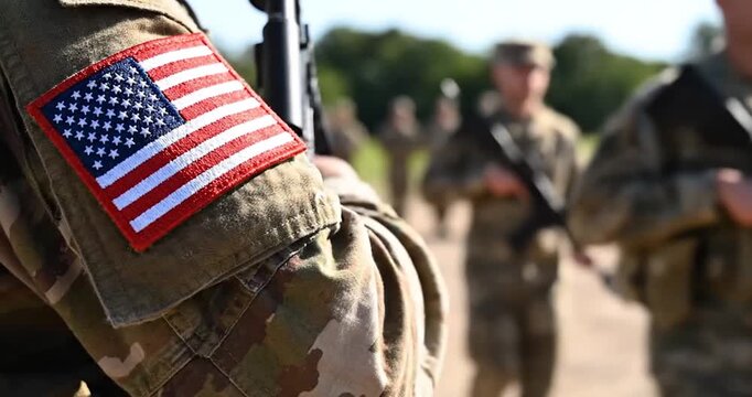 US military soldier uniform with flag patch and blurry background troops