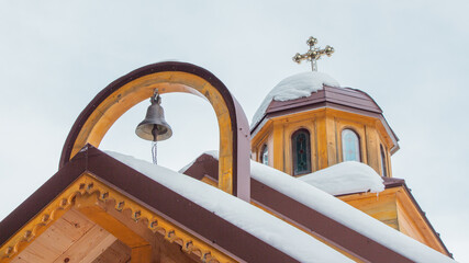Close-up of an ancient wooden Orthodox church dome with a cross and a bell, traditional religious...