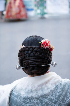 Fallera woman wearing traditional coiled braids hairstyle with pin
