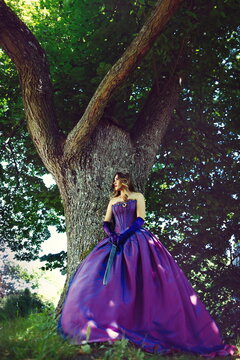 Dramatic Fantasy Woman in Purple Gown with Sword by Ancient Tree