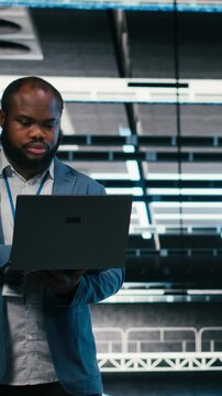 Vertical video Team of server farm software developers using laptop to optimize electronics. Data center teamworking colleagues brainstorming, using notebook to monitor system performance bottlenecks