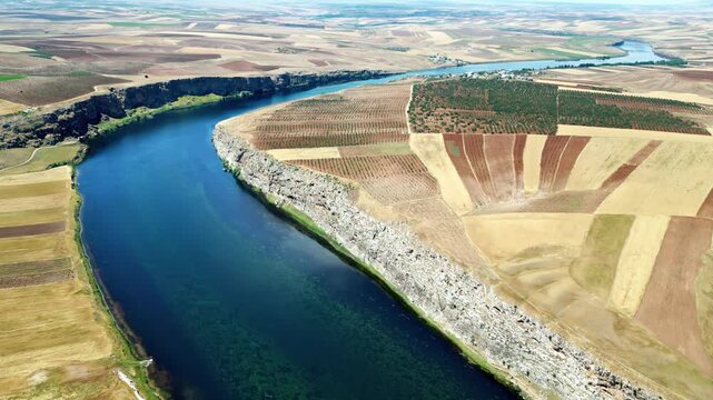 Aerial drone view of the Tigris River winding through agricultural fields and cliffs in the Mesopotamia region of southeastern Turkey, showing fertile farmland and dramatic river landscapes