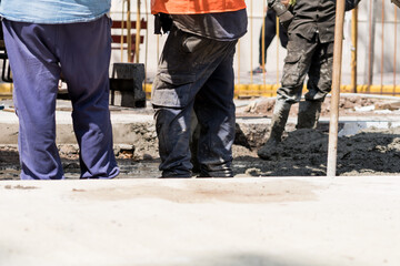 Construction workers pouring wet cement on a busy urban street during daytime