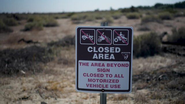 Sign shows closed area at Dos Palmas oasis. Signs inform of restrictions on motorized vehicle access for visitors.