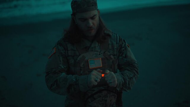 American Military Man Lights Chemical Light on Beach Near Ocean At Night