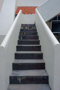 Concrete outdoor staircase with white side walls leading upwards, architectural perspective in natural daylight.