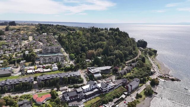 Cinematic aerial shot moving forward toward the 30-meter monumental cross atop Cerro Philippi, revealing the lush native Valdivian forest and Lake Llanquihue in Puerto Varas, Chile