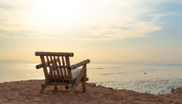 Empty wooden chair overlooking the tranquil sea at sunrise In Dahab