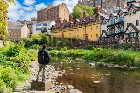 A man is enjoying beautiful view at Dean Village, Edinburg, Scotland. A picturesque, tranquil oasis, formerly an industrial milling hub for over 800 years, now features quaint 19th-century stone house