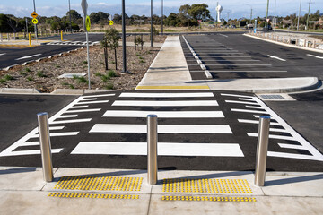 Raised pedestrian crossing with tactile paving and bollards in a newly developed urban car park in Australia. Clear road markings, accessible design and empty parking space. Modern infrastructure © Doublelee