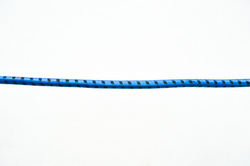 Horizontal shot of a blue and black patterned elastic cord isolated on a white background. Simple minimalist composition, industrial string, and textile detail. © Setyotuhu