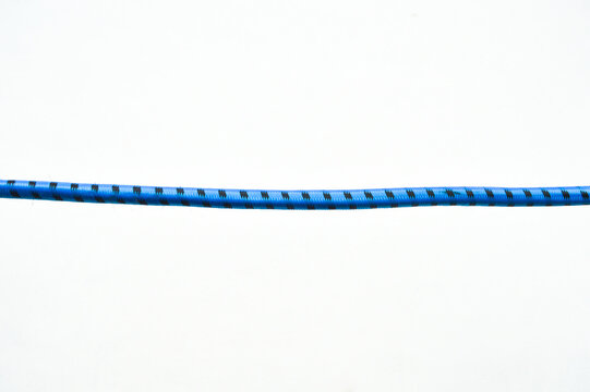 Horizontal shot of a blue and black patterned elastic cord isolated on a white background. Simple minimalist composition, industrial string, and textile detail.